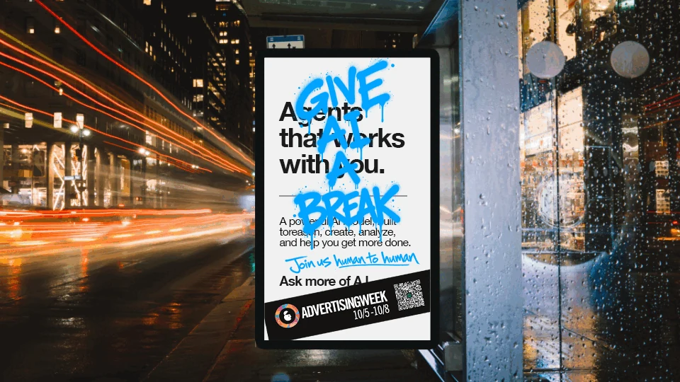 Advertising Week New York Give AI a Break digital out-of-home screen with blue handwritten creative, event branding and a QR code in a nighttime city setting.