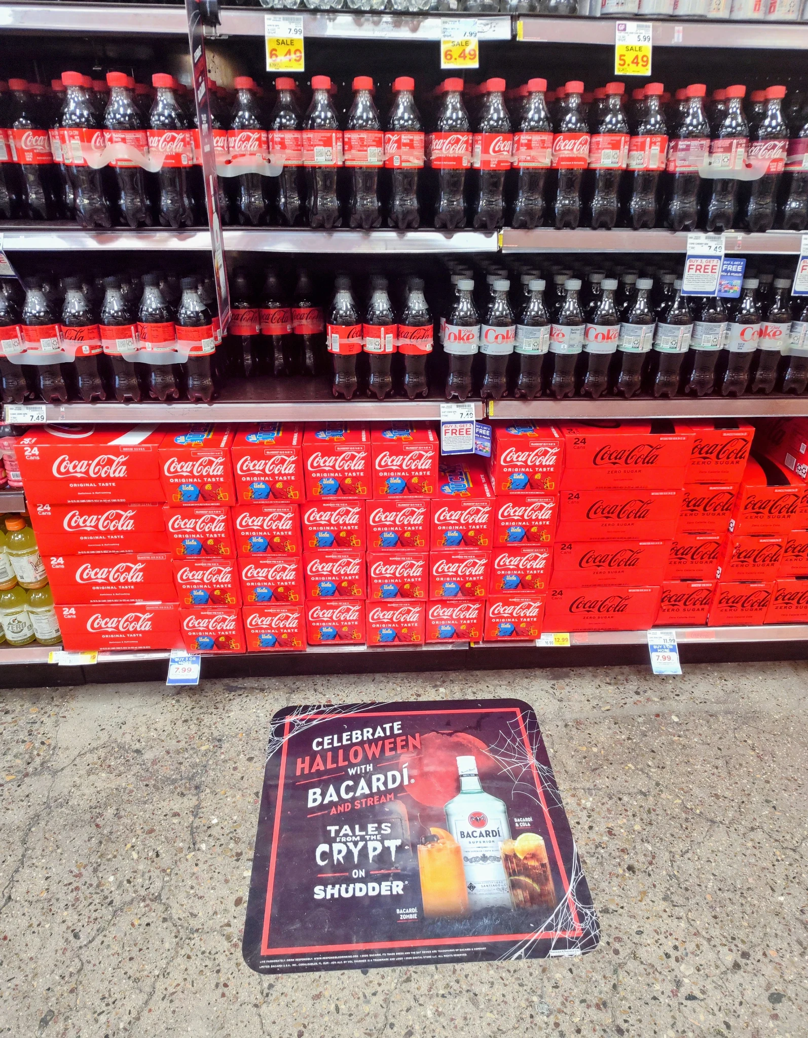 Bacardí Halloween floor advertising graphic installed in a Ralphs beverage aisle in front of Coca-Cola products as an in-store point-of-purchase retail media campaign.