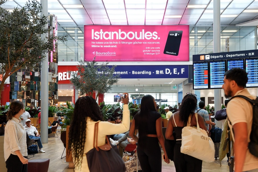 BoursoBank Istanboules travel advertising on an overhead digital billboard by airport departures and boarding signage in Paris.