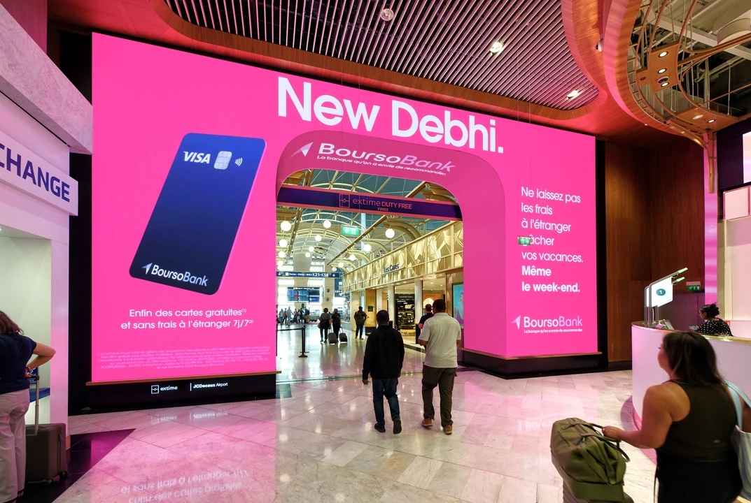 BoursoBank New Debhi airport DOOH advertisement on the pink Shopping Digital Arch at Paris Charles de Gaulle, showing a Visa card and passenger walkway.