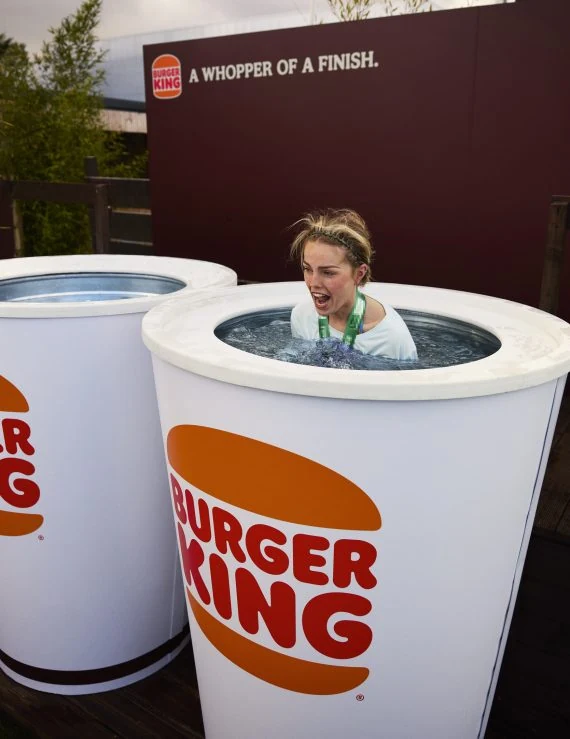 Marathon runner smiling inside a giant Burger King cup-shaped ice bath at the Dublin Marathon post-race activation.