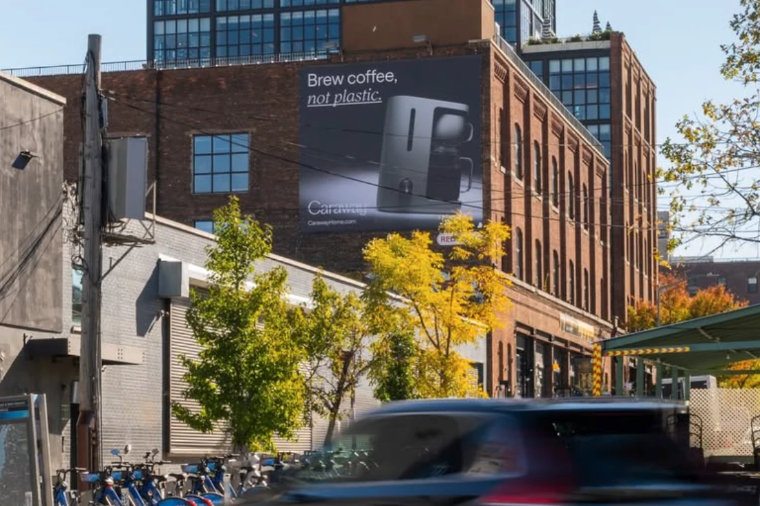 Caraway Home large-format OOH advertisement reading Brew coffee, not plastic next to the brand's coffee maker.