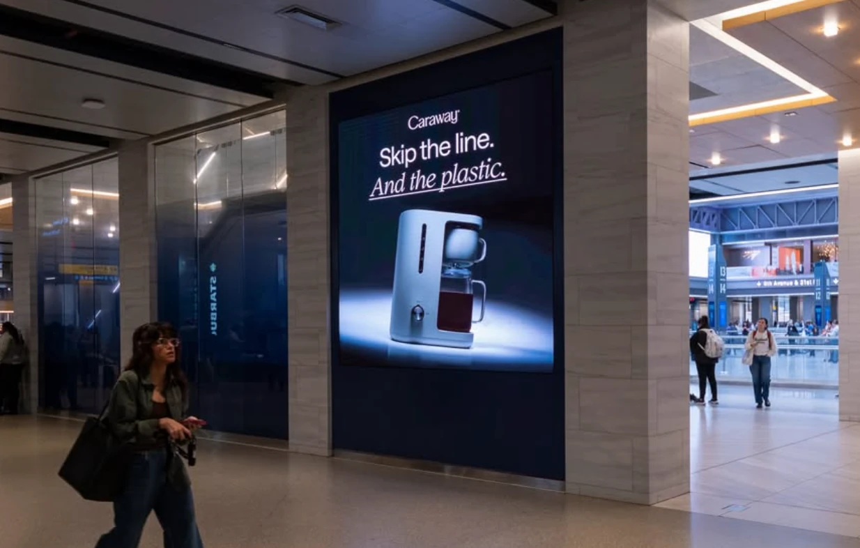 Caraway Home indoor digital advertisement reading Skip the line. And the plastic. with a product image of the coffee maker.