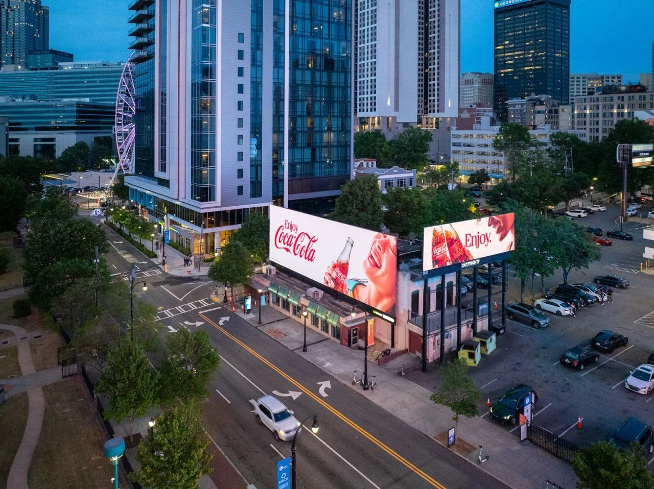 Two large Coca-Cola billboards in an urban setting using Enjoy Coca-Cola messaging, bottle imagery and lifestyle photography.
