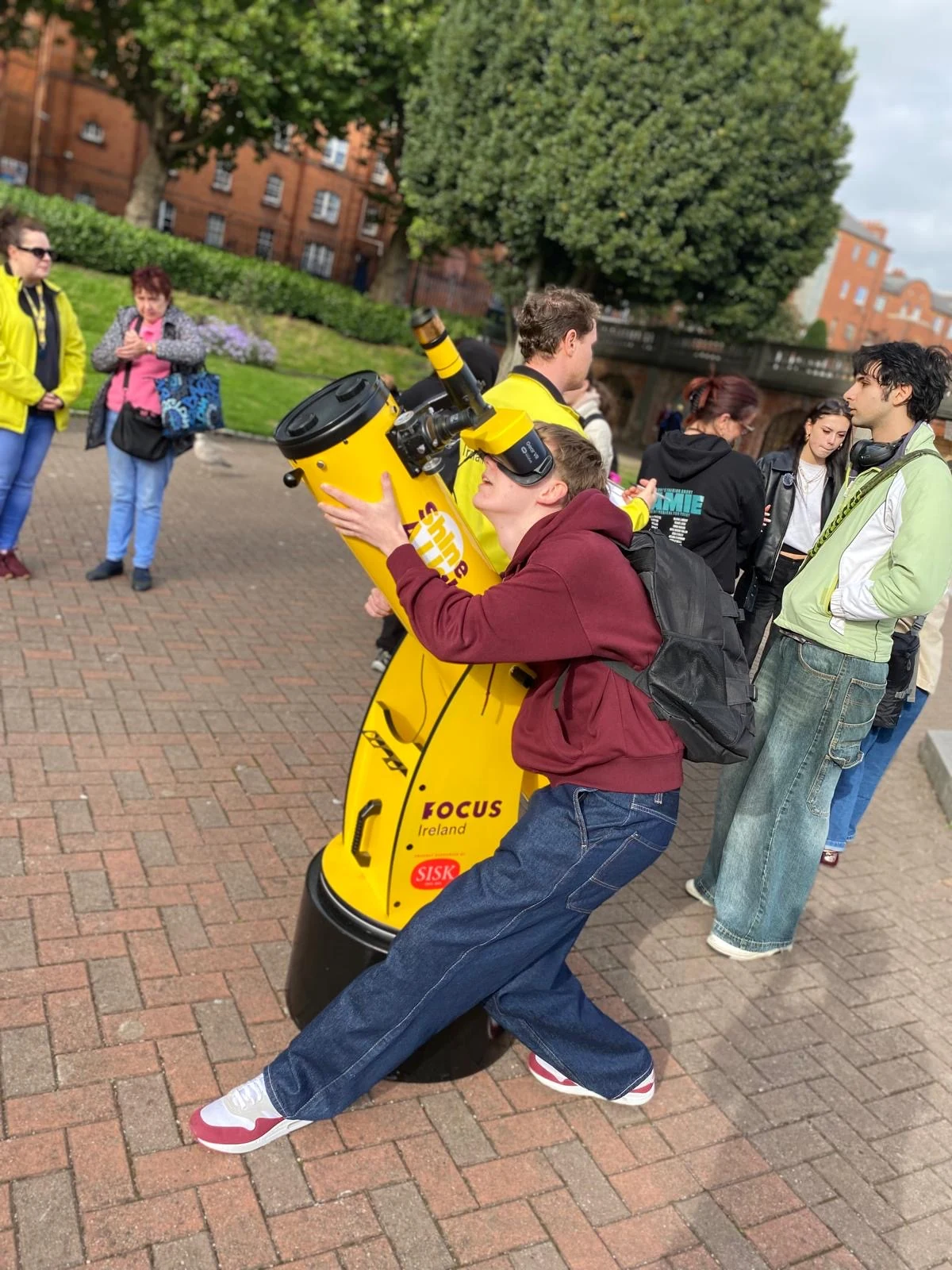 Visitor using the yellow Focus Ireland Shine A Light Stargazer telescope installation in St. Patrick’s Park, Dublin, created to raise awareness of child homelessness.