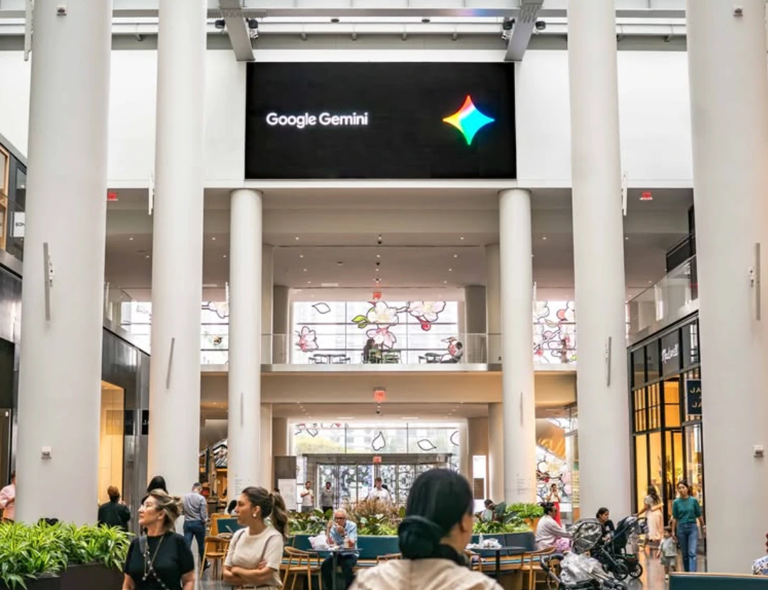 Large Google Gemini digital screen positioned above a busy Brookfield Place atrium with shoppers and visitors below.