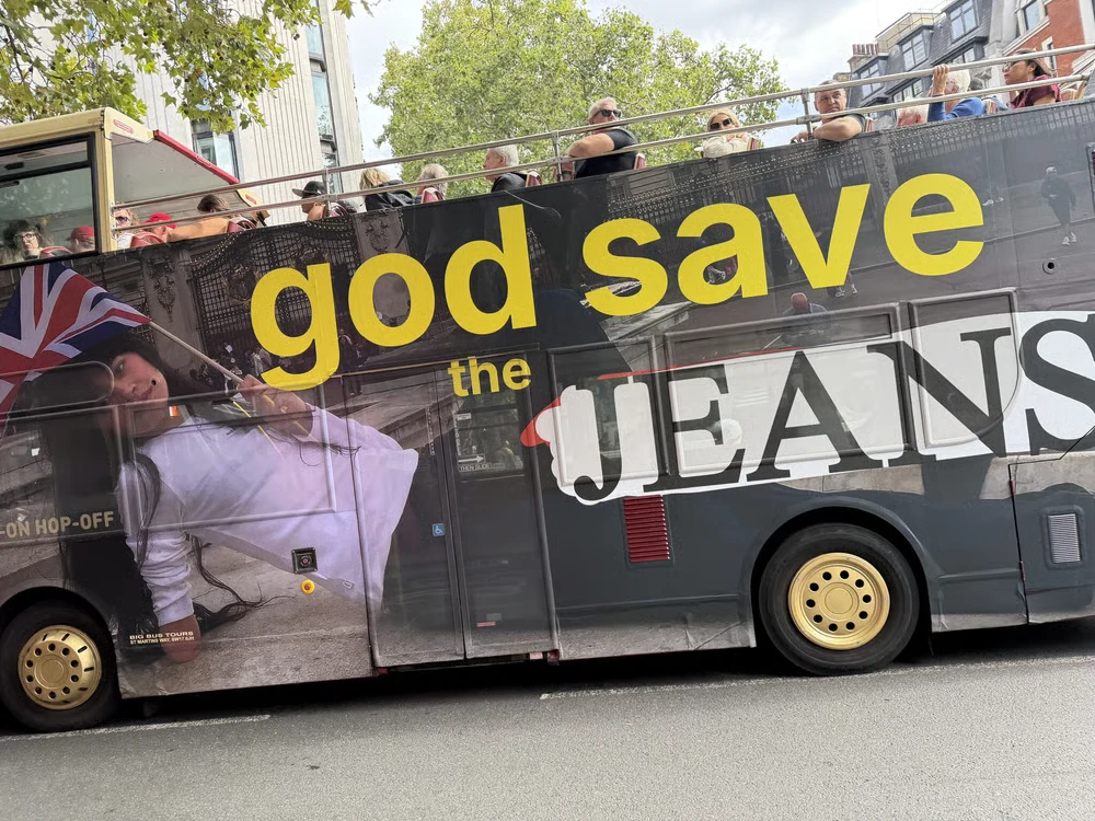 Guess Jeans London double-decker bus takeover featuring the phrase god save the JEANS, a Union Jack and oversized fashion portrait imagery.
