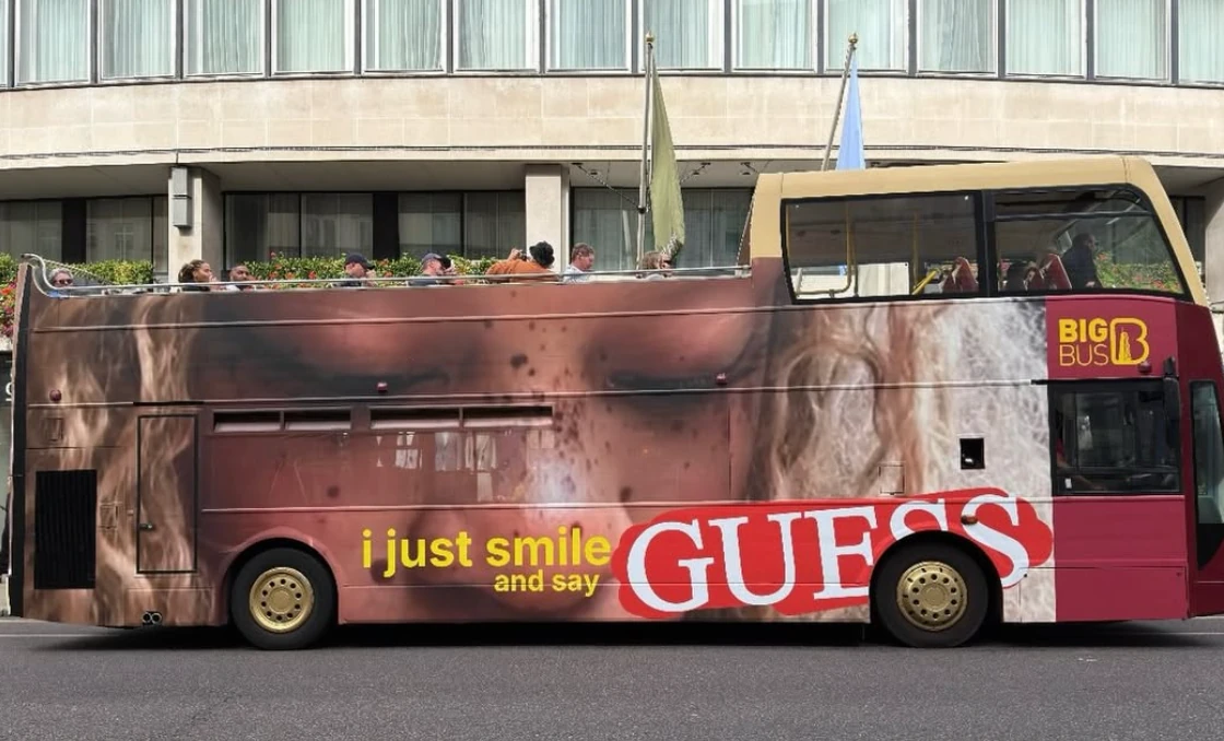 Guess Jeans London bus campaign featuring a close-up portrait and the phrase i just smile and say GUESS.