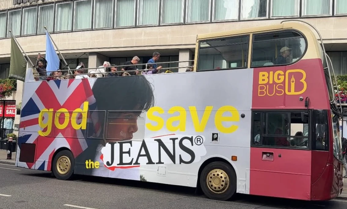 Guess Jeans branded London double-decker bus featuring oversized GUESS JEANS typography and fashion portrait imagery.