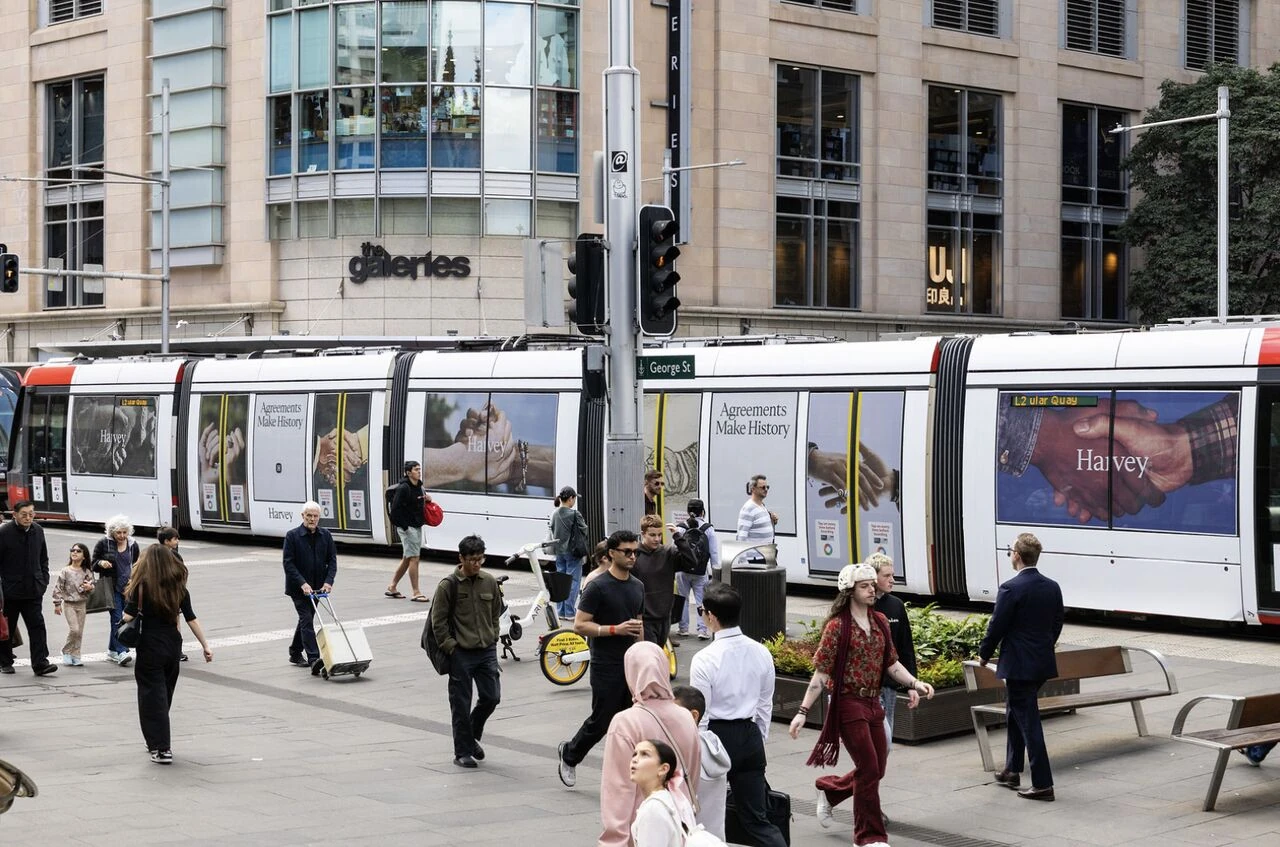 Harvey AI Agreements Make History campaign displayed as a full tram advertising wrap in Sydney with hands and Harvey branding.