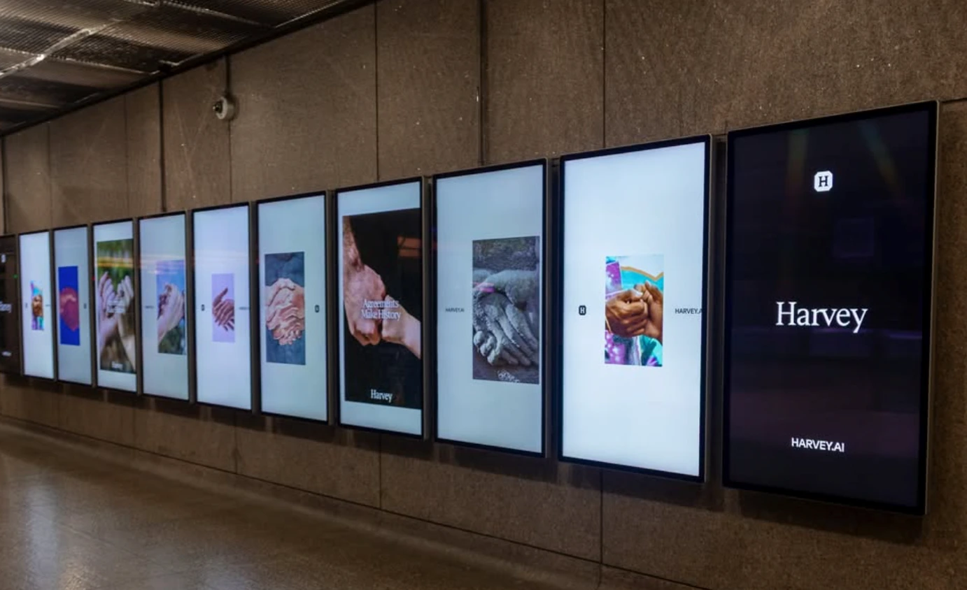 Harvey multi-screen digital campaign showing a sequence of Agreements Make History hand images in an indoor transit environment.