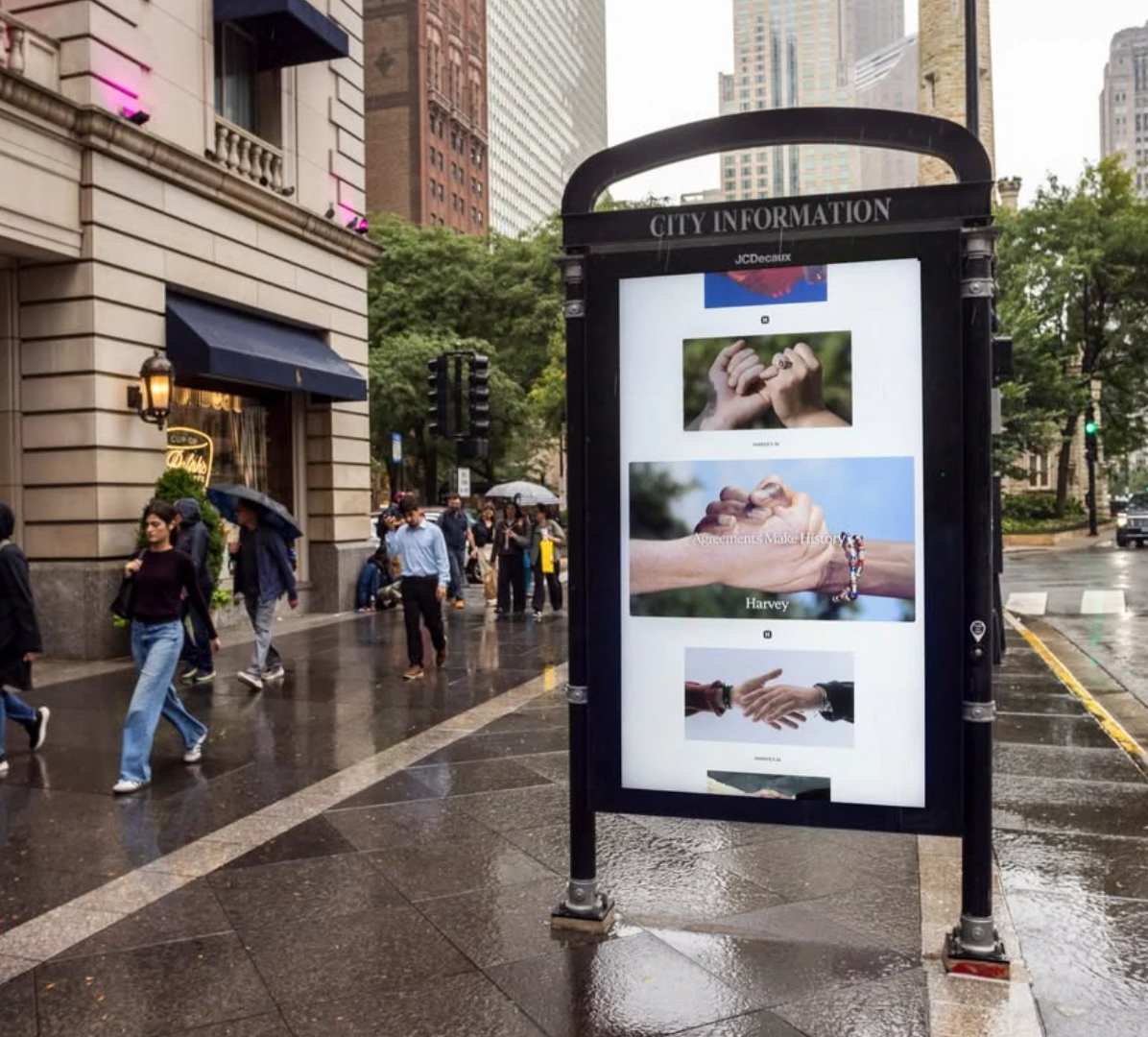 Harvey street furniture digital display showing several Agreements Make History hand images in a vertical editorial layout.