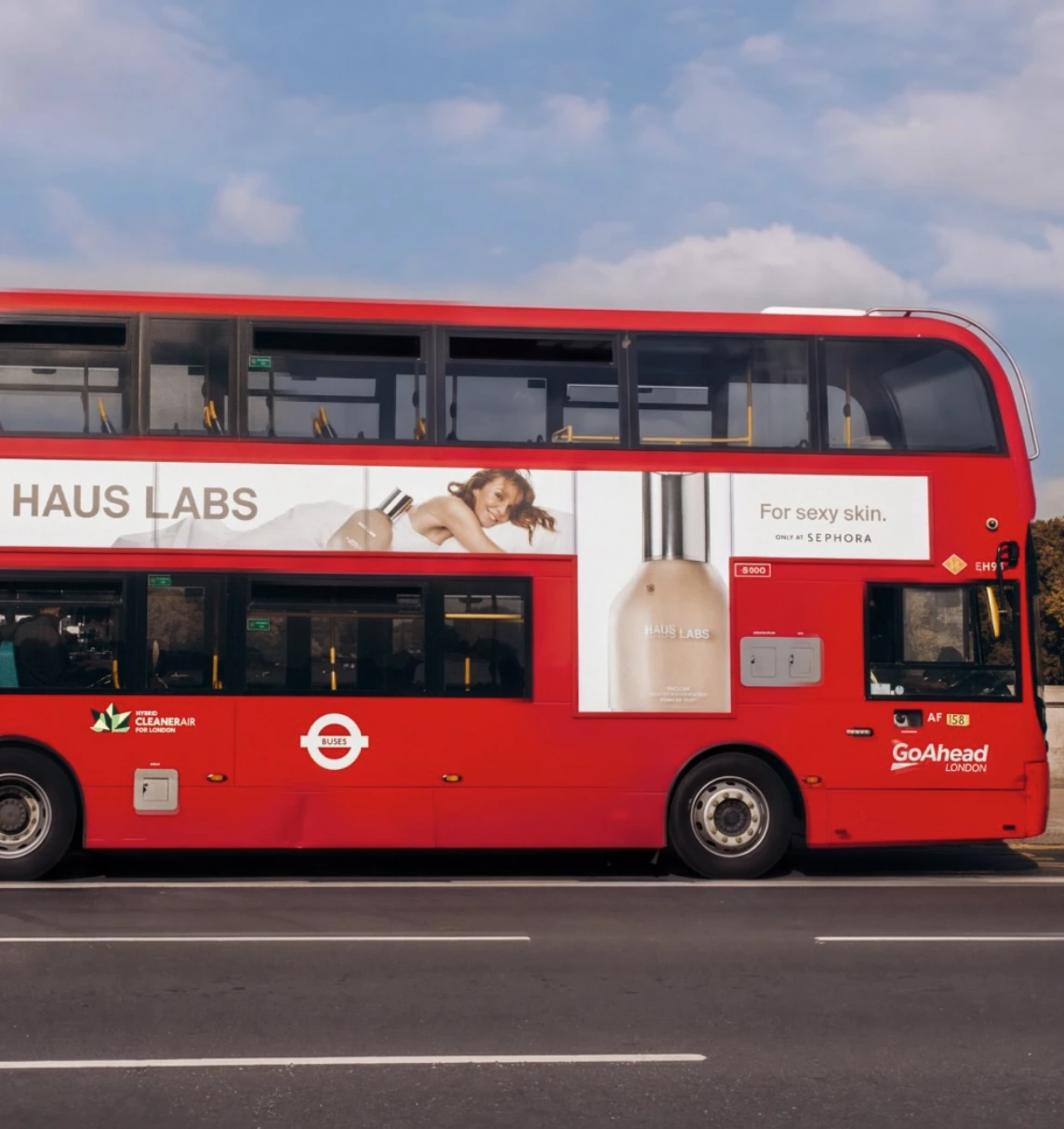 Red London double-decker bus carrying a Haus Labs For sexy skin campaign with product imagery and Only at Sephora messaging.