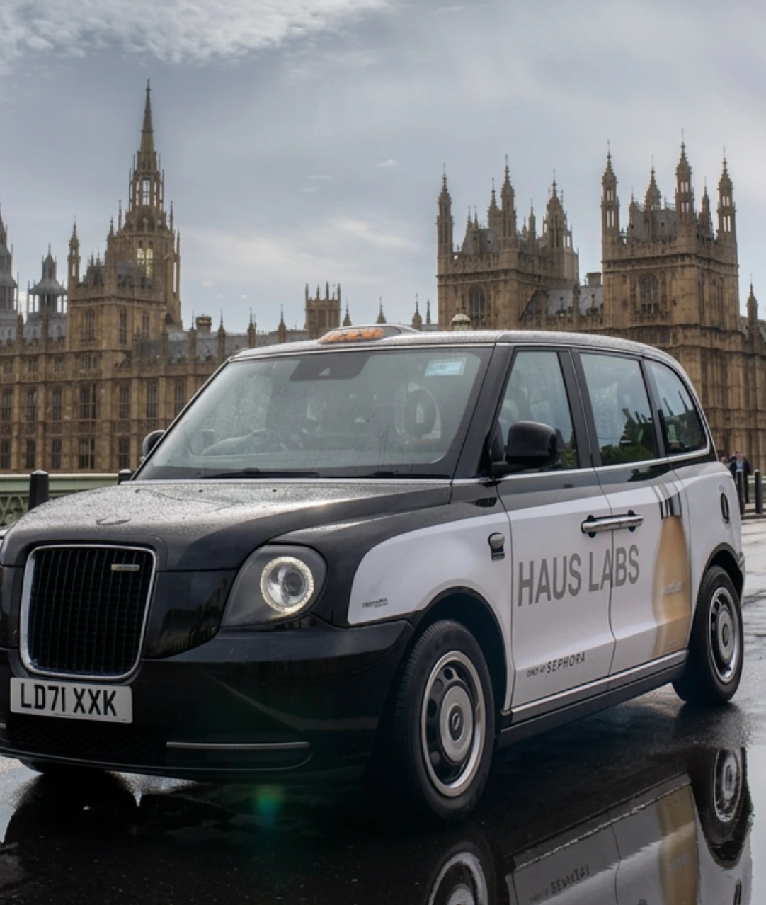 Haus Labs branded London black cab promoting Sephora availability in front of the Palace of Westminster.