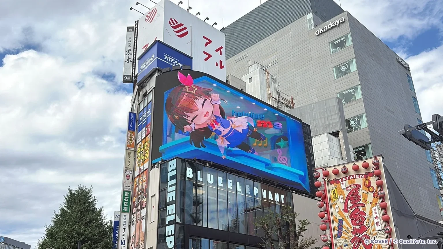 hololive Dreams 3D digital billboard in Shinjuku featuring a holodori character on a giant curved screen above the street.