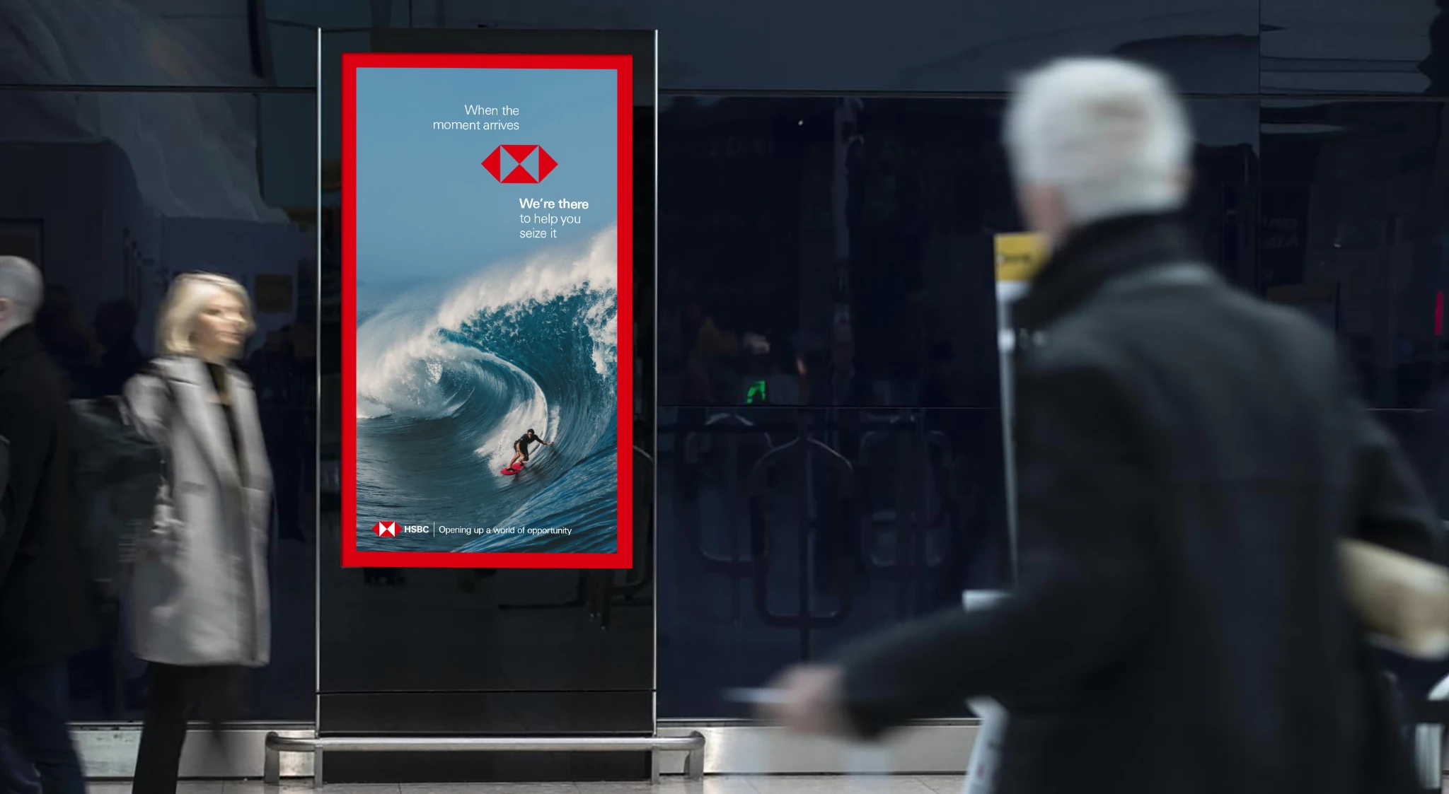 HSBC digital out-of-home advertisement showing a surfer riding a large wave with the message When the moment arrives, we’re there to help you seize it.