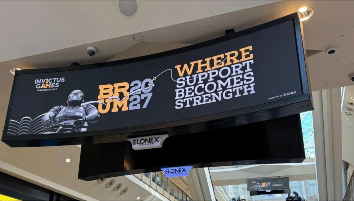 Curved Elonex digital screen displaying Invictus Games Birmingham 2027 BRUM 27 creative in a Birmingham retail environment.