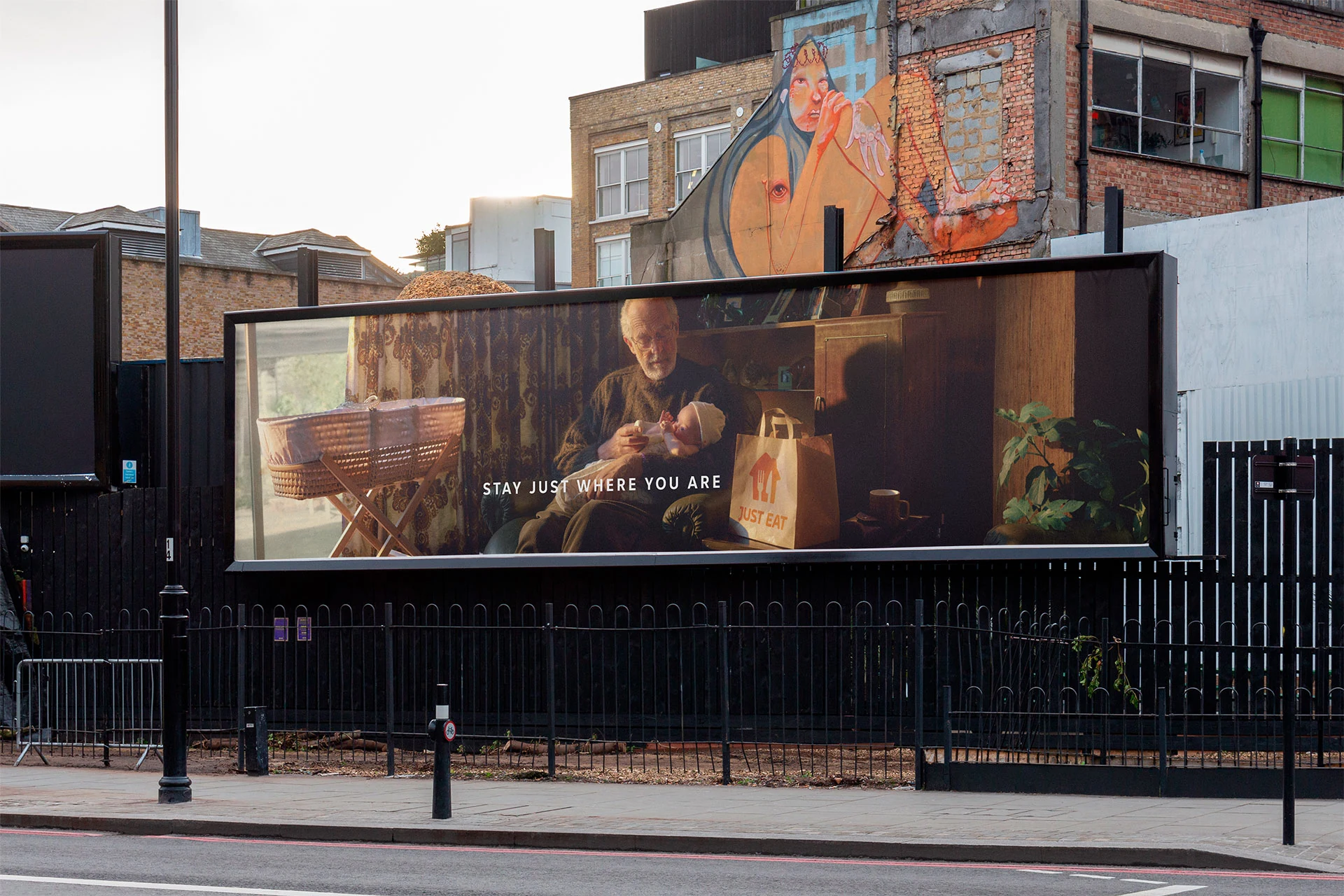 Just Eat and VCCP outdoor advertising billboard featuring a grandfather feeding a baby beside a Just Eat delivery bag and Stay Just Where You Are messaging.