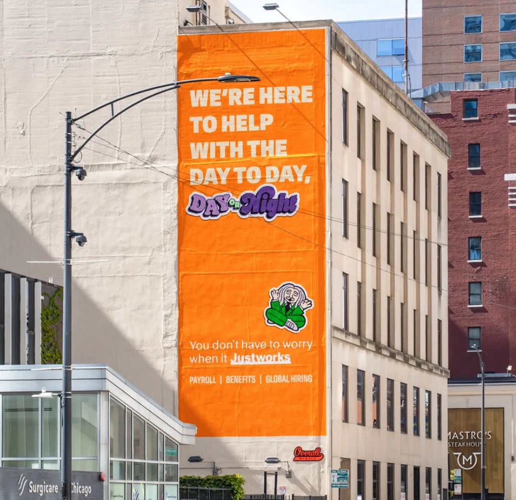 Justworks orange wall mural reading We're here to help with the day to day, day or night.