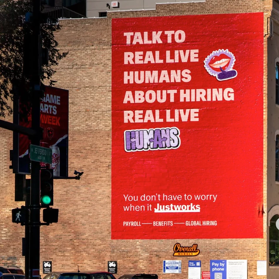 Justworks red wall mural reading Talk to real live humans about hiring real live humans.
