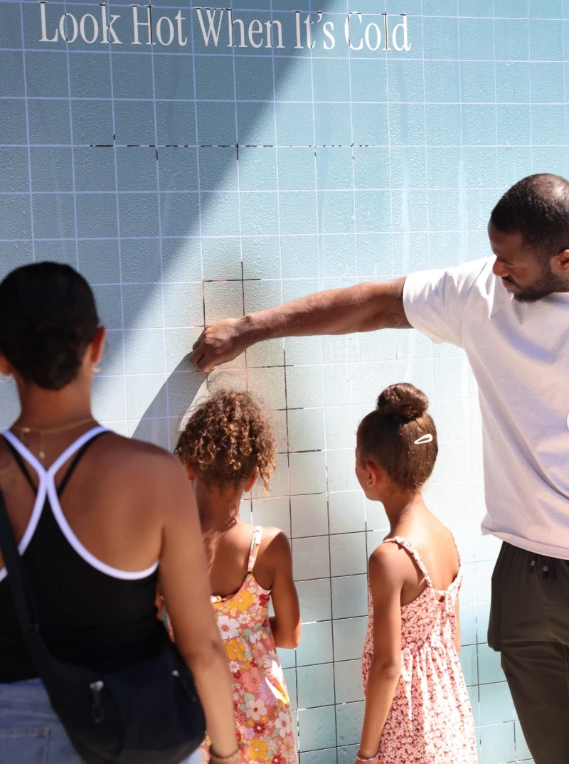 Visitors interacting with the Khloé x Fabletics Look Hot When It’s Cold peel-off wall in Century City, Los Angeles.