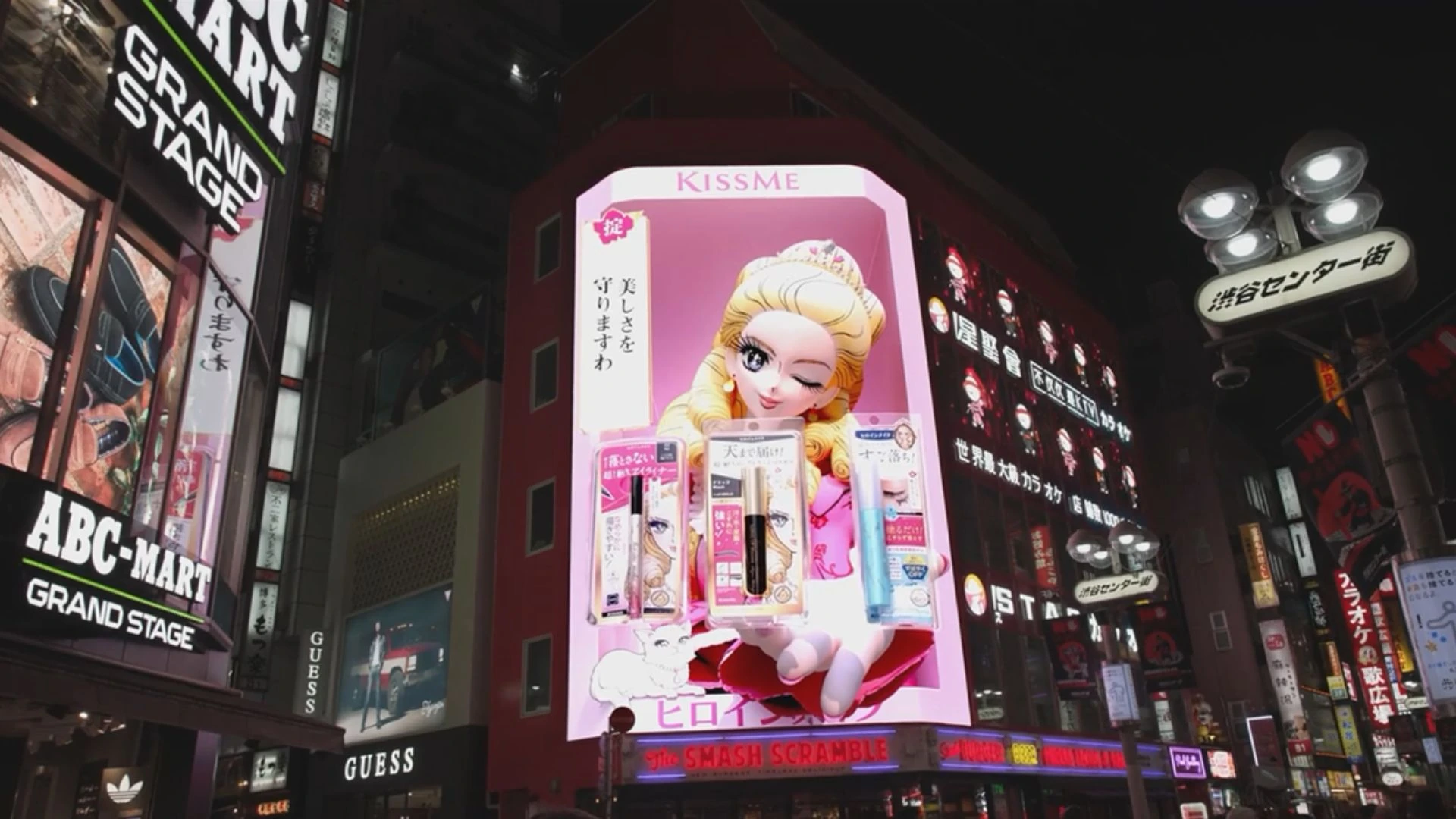 Nighttime street view of the KISSME Heroine Make 3D DOOH advertising screen in Shibuya, Tokyo, surrounded by illuminated retail signage.