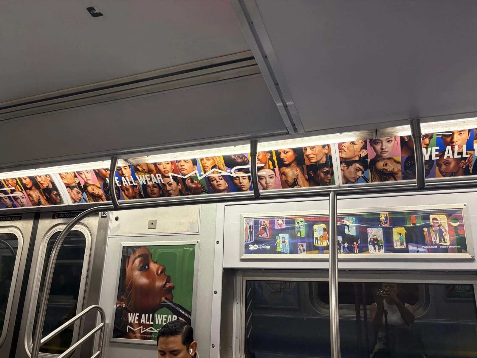 Interior New York subway advertising for MAC Cosmetics We All Wear MAC with portrait car cards and repeated campaign branding.