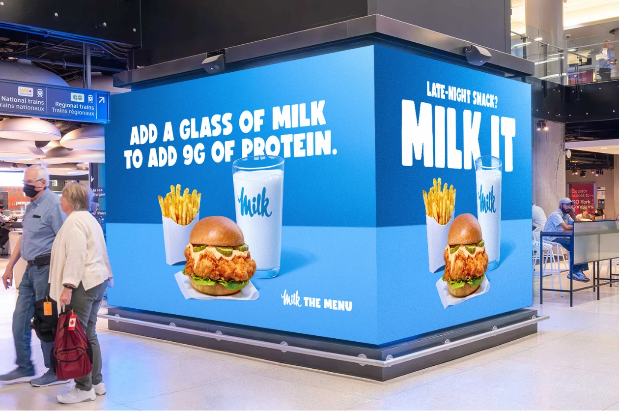 Milk the Menu digital OOH installation at Union Station showing a chicken sandwich, fries and a glass of milk with messaging about adding 9g of protein.