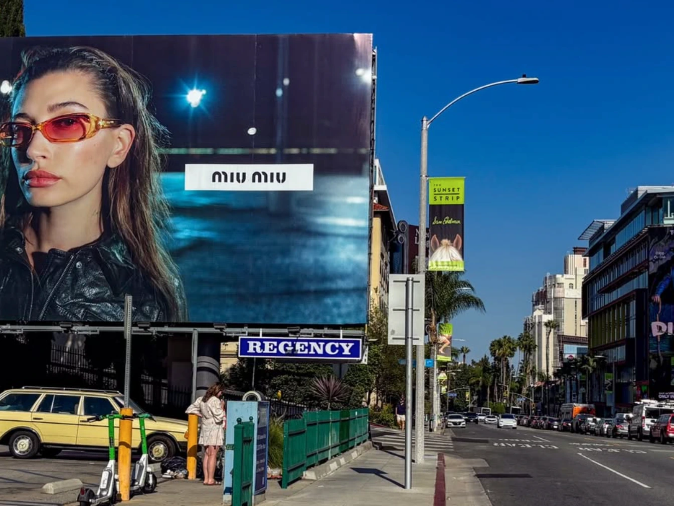 Close street-level view of the Miu Miu Fall Winter 2026 large-format billboard on Sunset Strip in Los Angeles.