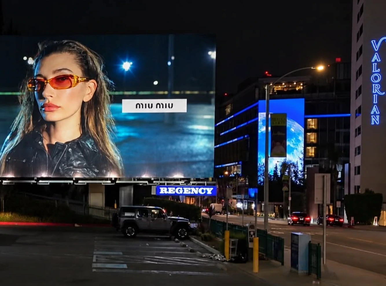 Illuminated Miu Miu Fall Winter 2026 billboard on Sunset Strip in Los Angeles at night.
