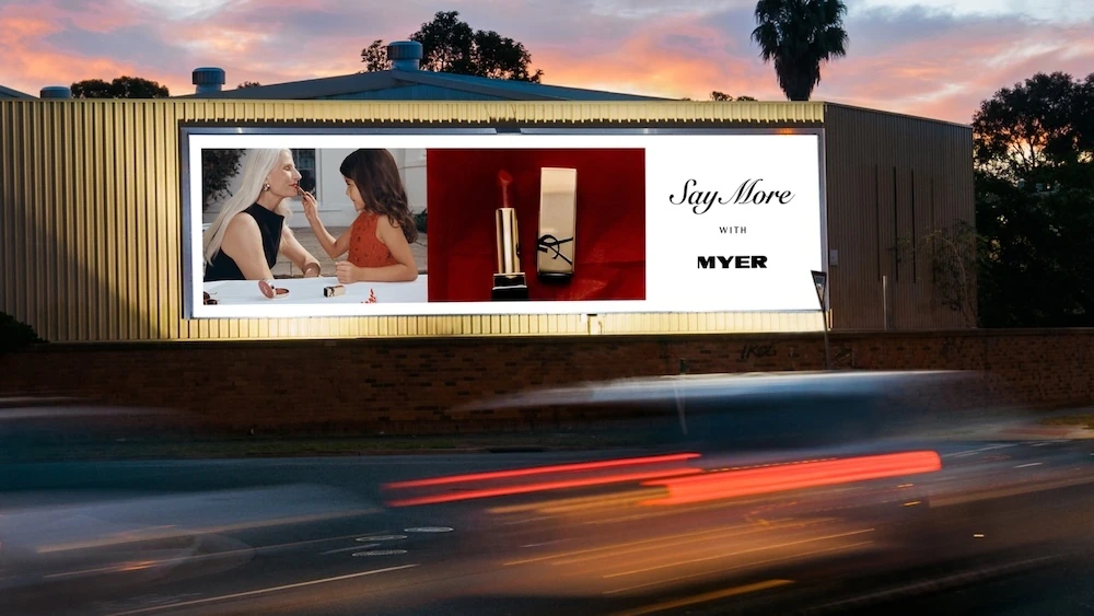 Illuminated roadside billboard for Myer Christmas campaign featuring family beauty imagery and the Say More with Myer message.