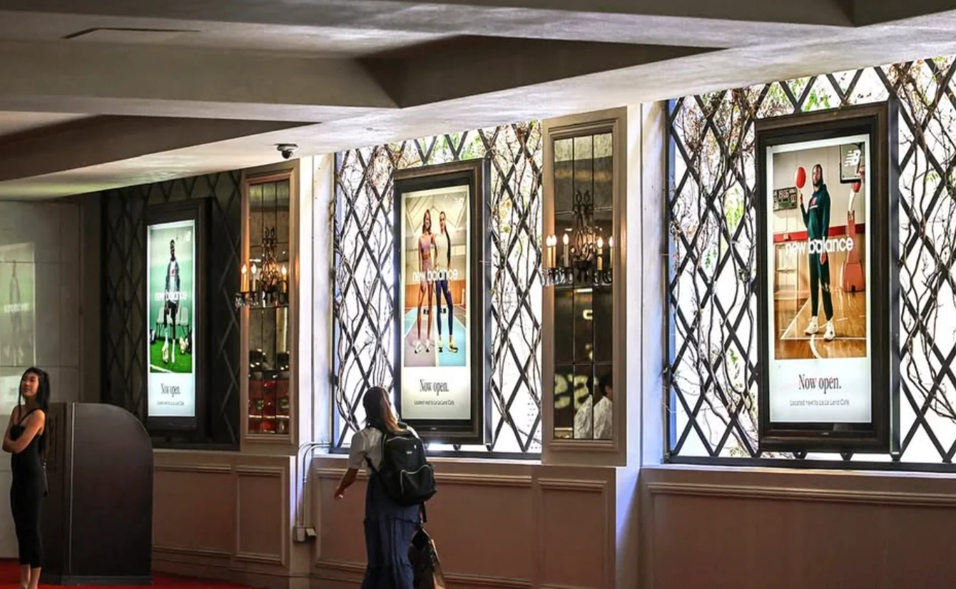 Illuminated New Balance retail OOH displays along a pedestrian corridor at The Grove featuring multiple athlete creatives.