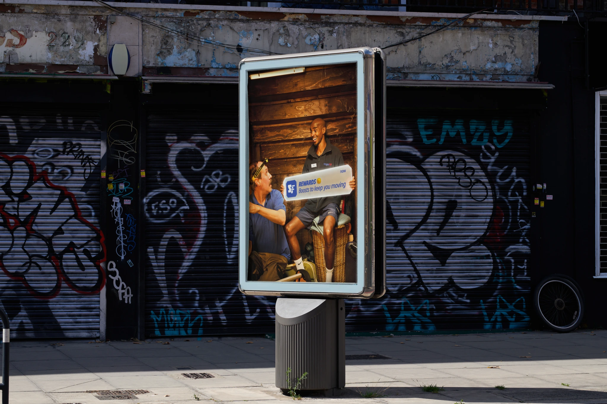 Screwfix Rewards outdoor advertising showing Sir Mo Farah inside a street lightbox presenting a Rewards notification.