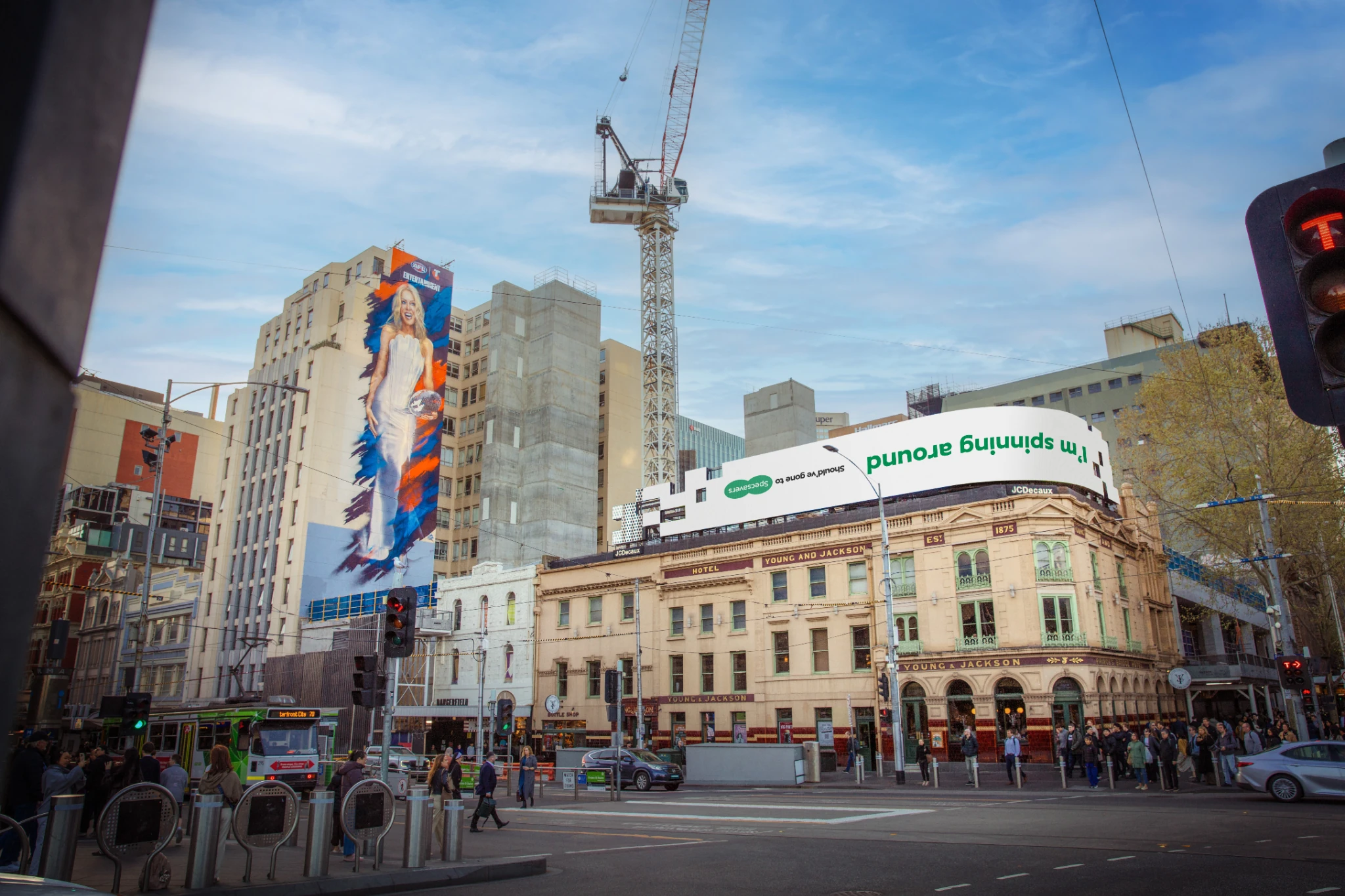 Specsavers out-of-home billboard near Young and Jackson in Melbourne displaying the phrase I’m spinning around upside down beneath the Kylie mural.