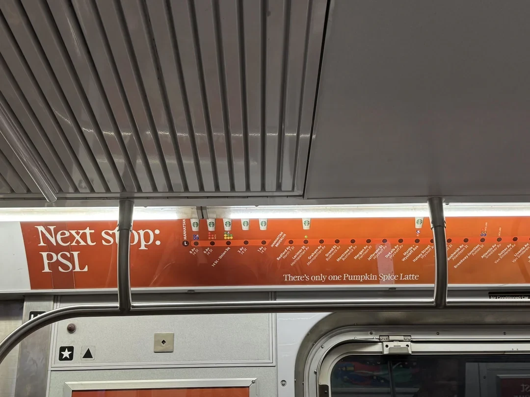 Starbucks Pumpkin Spice Latte interior subway advertisement on the MTA L train reading Next stop PSL with a route-style map.