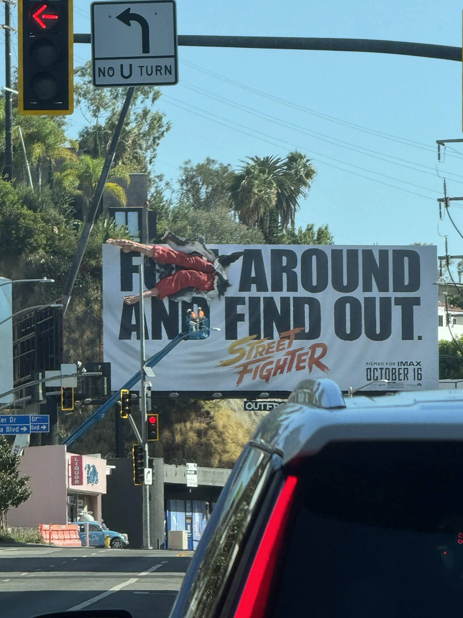 Street Fighter IMAX billboard at a Los Angeles intersection featuring the F Around and Find Out headline and a fighter protruding through the billboard.