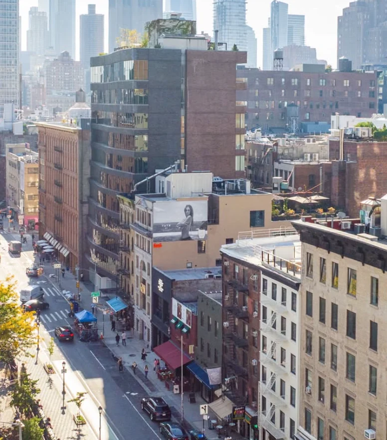 Aerial city view showing the Tate McRae TATE 01 fragrance campaign on a SoHo building in New York City.