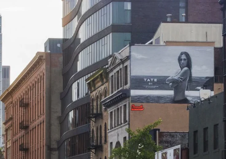 TATE 01 fragrance wallscape featuring Tate McRae visible among SoHo buildings in New York City.