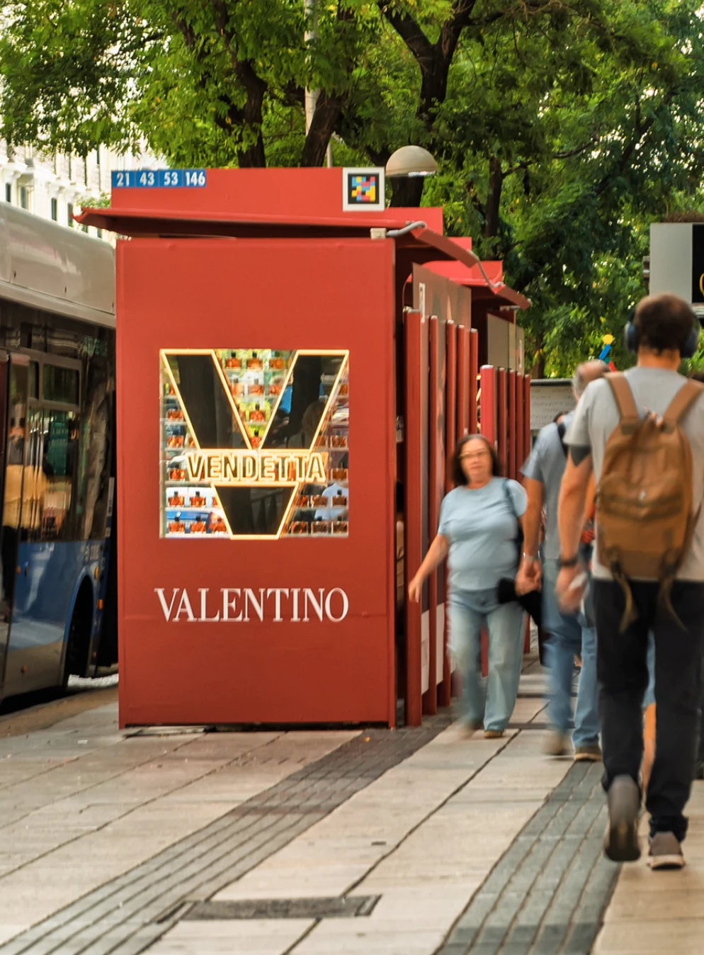 Valentino Vendetta red bus shelter installation with illuminated V display and Valentino branding beside pedestrians.