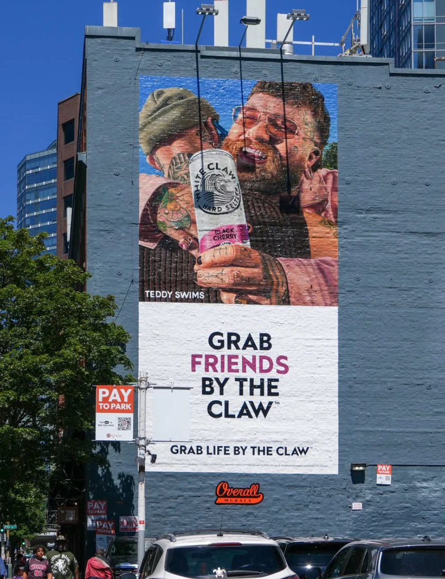Close view of a White Claw wallscape featuring Teddy Swims, Black Cherry product imagery and Grab Friends by the Claw messaging.