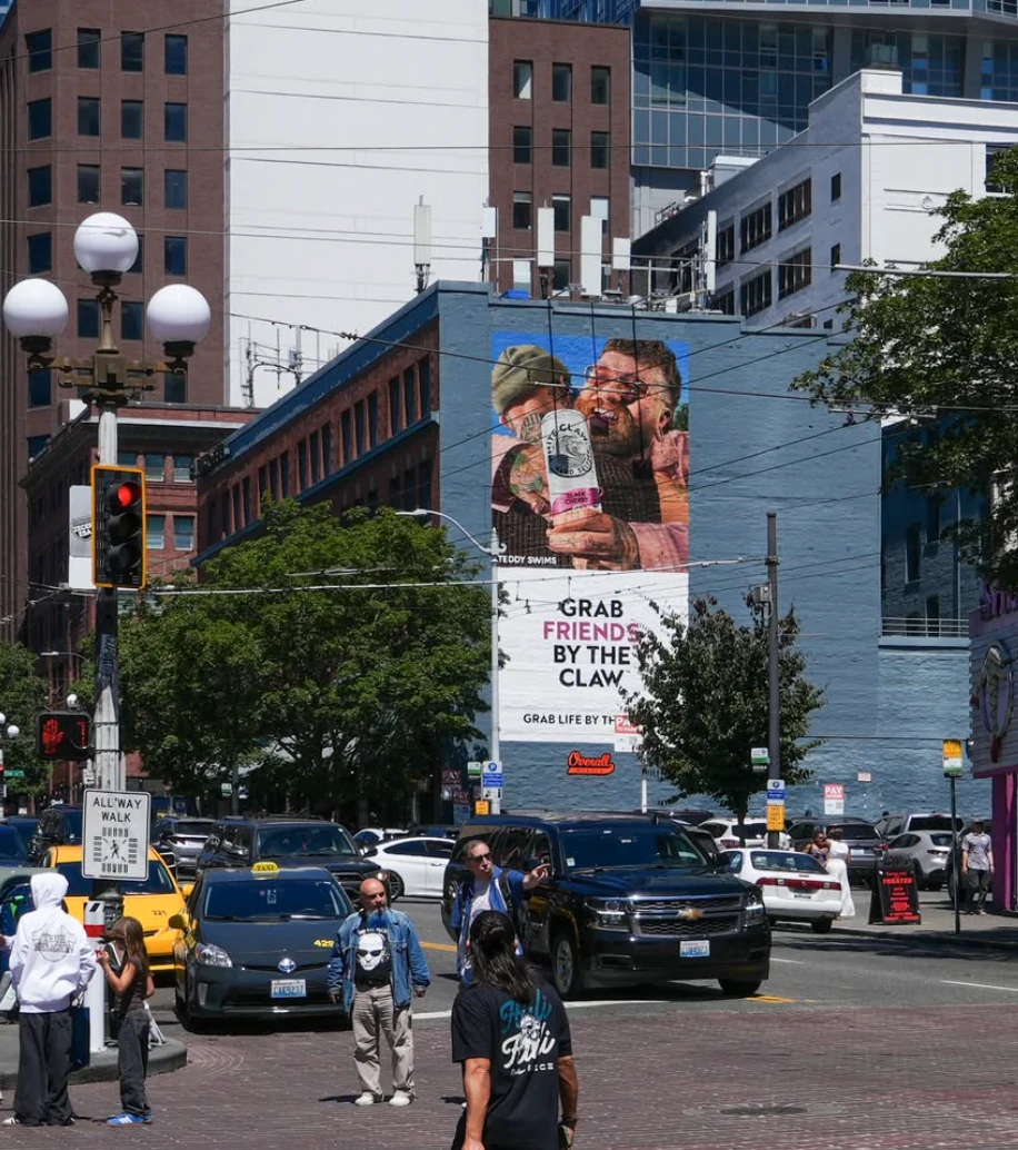Large White Claw and Teddy Swims mural advertising creative visible above a busy city street.