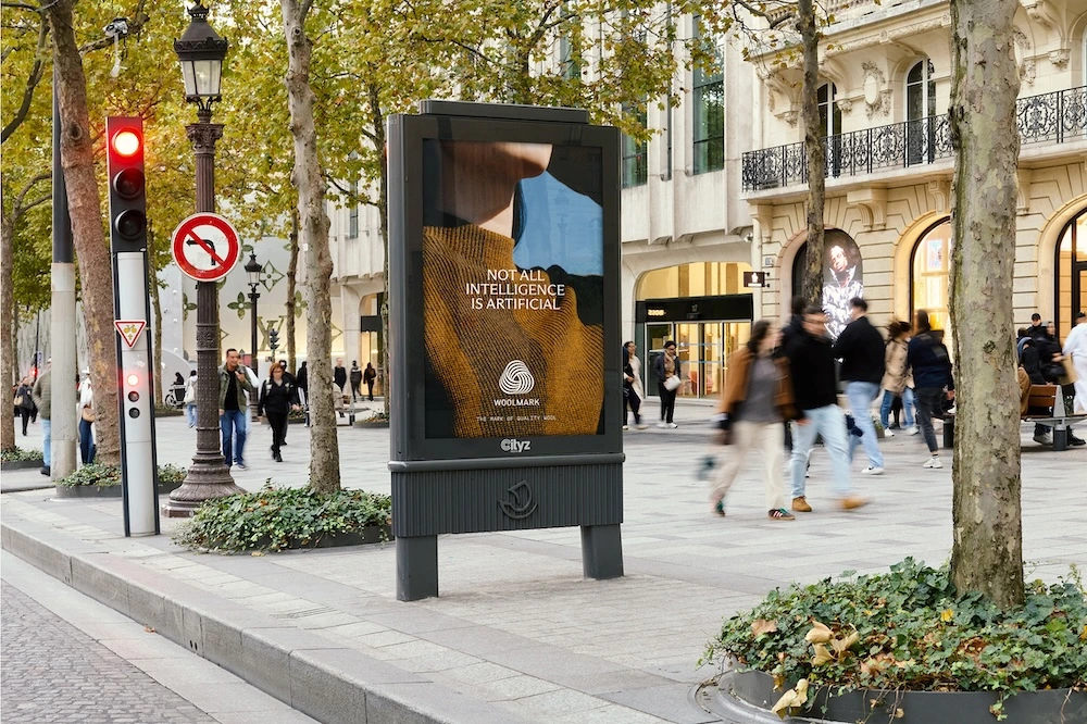 Woolmark street-level OOH in a European city with the line Not all intelligence is artificial over a close-up wool fashion image.