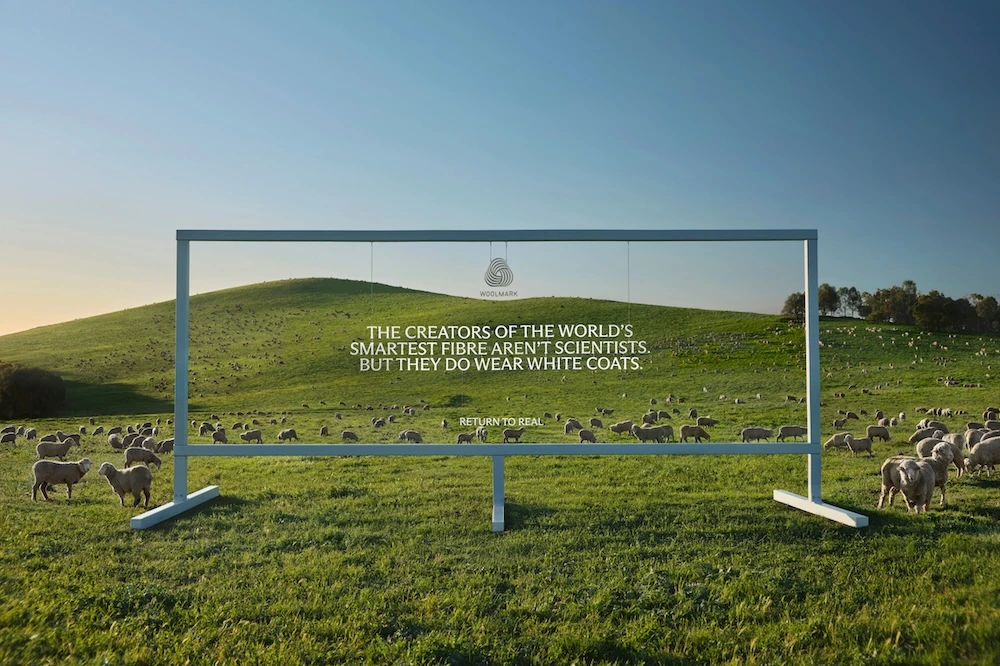 Woolmark Return to Real outdoor execution in a field of sheep with the line The creators of the world’s smartest fibre aren’t scientists, but they do wear white coats.