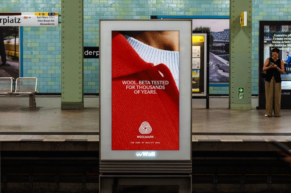 Woolmark transit OOH showing a close-up of red wool with the line Wool beta tested for thousands of years.