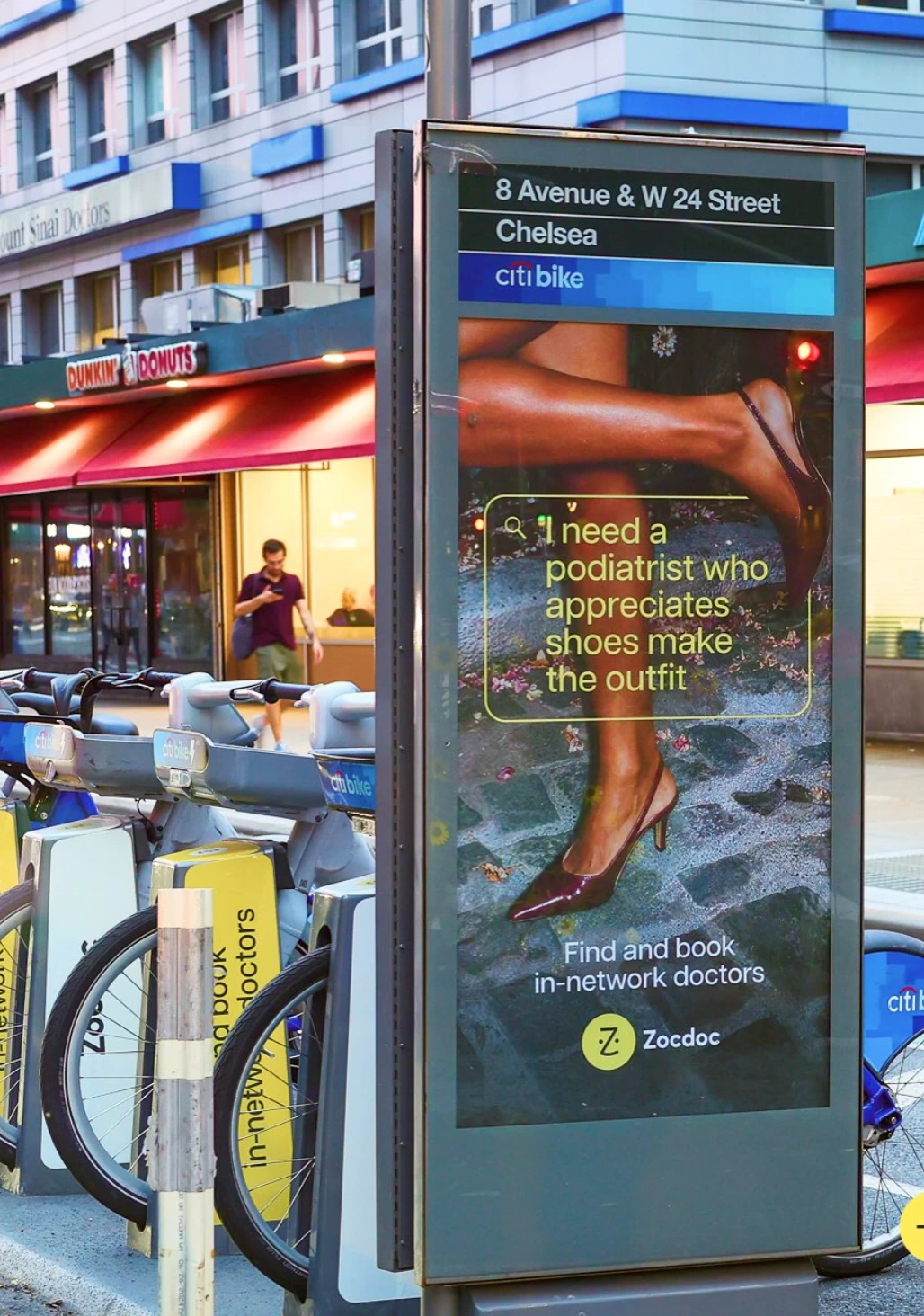 Zocdoc street panel in Chelsea New York beside Citi Bike featuring a playful podiatrist search query.