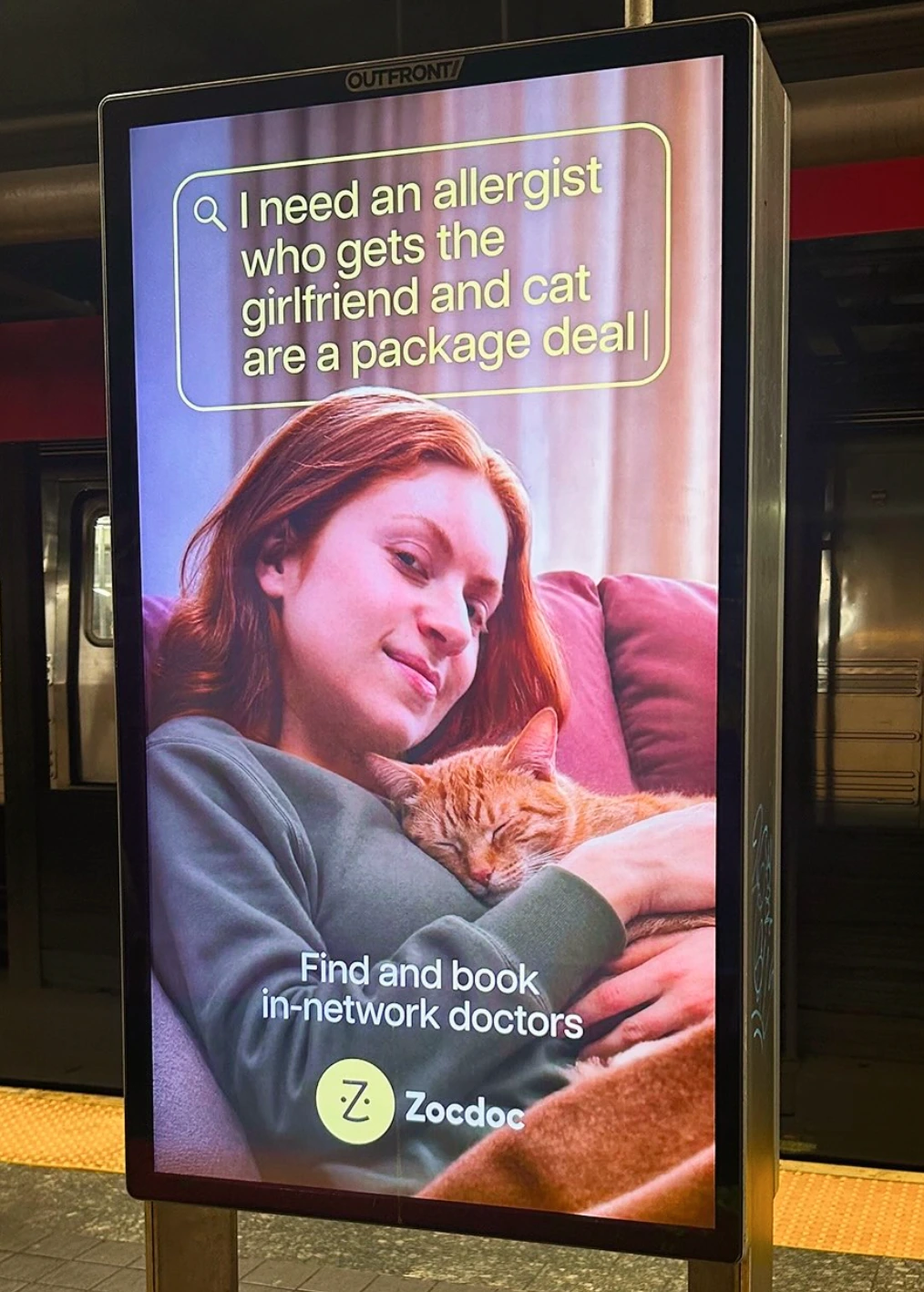 Zocdoc subway digital ad featuring a woman holding a cat with a search query about finding an allergist.